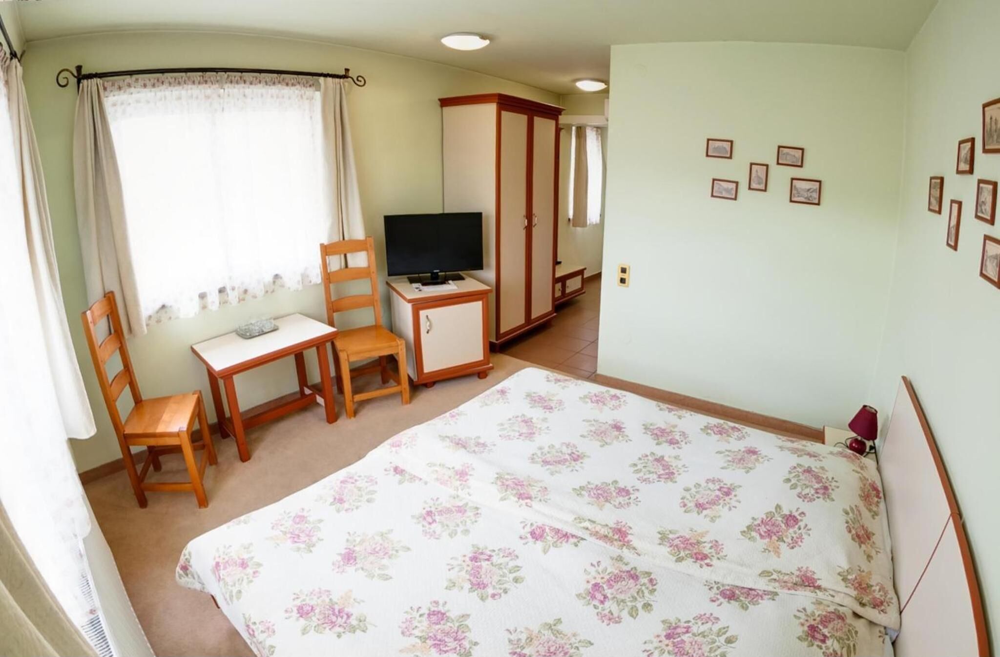 A bedroom with a bed, a desk, a chair, a TV, and a wardrobe.