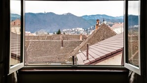A view from a window overlooking a town with a prominent church steeple and mountains in the background. - Pensiunea Luiza (Brasov)