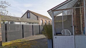 A gated courtyard with a building featuring a brick facade and a sloped roof. - House Gite 6 persons near Illiers Combray LPE (Magny)