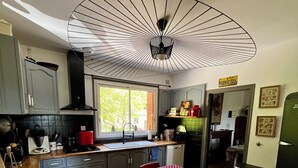 Keittiössä on ruokapöytä, tuoleja ja kattotuuletin.