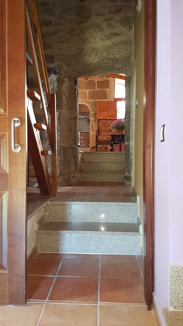Una escalera que lleva a una habitación con pared de piedra y puerta de madera.