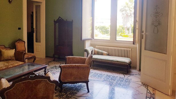 Una habitación con un ventanal grande, un radiador y una puerta con diseño decorativo.