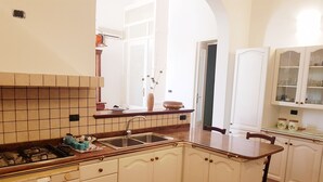 Una cocina con gabinetes blancos, salpicadero de azulejos, estufa a gas y un lavamanos.