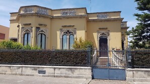 Un edificio histórico con detalles arquitectónicos ornamentales, una entrada con reja y una escalera que conduce a la entrada.