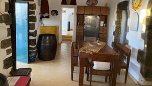 A compact kitchen with wooden cabinets, a central island, and a dining area with chairs and a table.