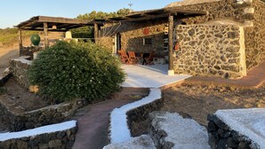 A stone building with a covered patio, outdoor seating, and a stone pathway.