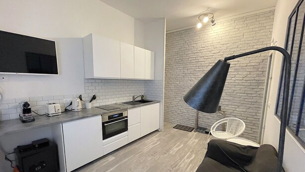 A modern kitchen with white cabinets, a black countertop, and a black floor lamp. - Apartment Trouville center (rue des Bains), near beach & casino (Trouville-sur-Mer)