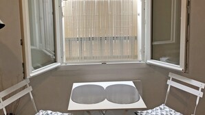 A small balcony with a table and two chairs, offering a view of a residential area with a fence and buildings. - Apartment Trouville center (rue des Bains), near beach & casino (Trouville-sur-Mer)