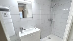 A modern bathroom with a white sink, mirror, and shower. - Apartment Trouville center (rue des Bains), near beach & casino (Trouville-sur-Mer)