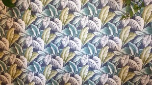 A room with a tropical leaf-patterned wallpaper, two white chairs, and a small round table. - Villa Flore - Loft - (Casteldaccia)