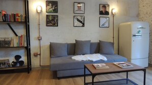 A cozy living room with a grey sofa, a coffee table, and a bookshelf filled with books. - Villa Flore - Loft - (Casteldaccia)