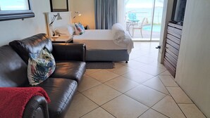 A hotel room with a bed, a sofa, a TV, and a view of the sea. - Bentley On The Beach (Durban North)