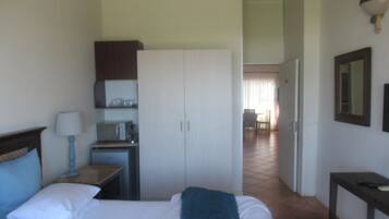 A hotel room with a bed, a desk with a lamp, a microwave, and a wardrobe.