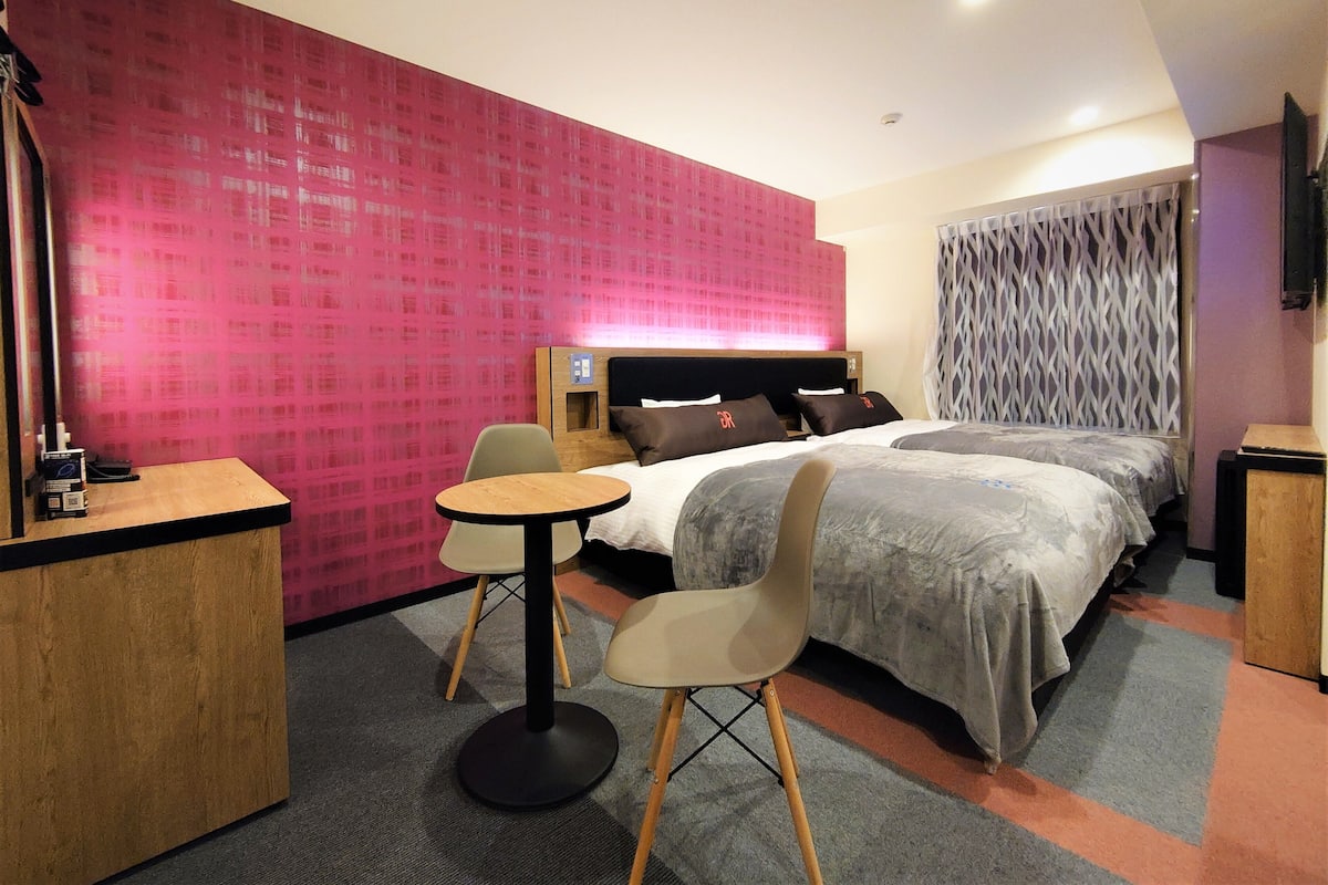 Una habitació d'hotel amb un llit gran, un escriptori i una cadira.