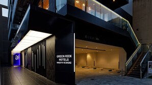 Una entrada de hotel moderna con fachada de vidrio, un letrero que dice 'Green Rich Hotels Nagoya Nishiki' y un piso de baldosas.