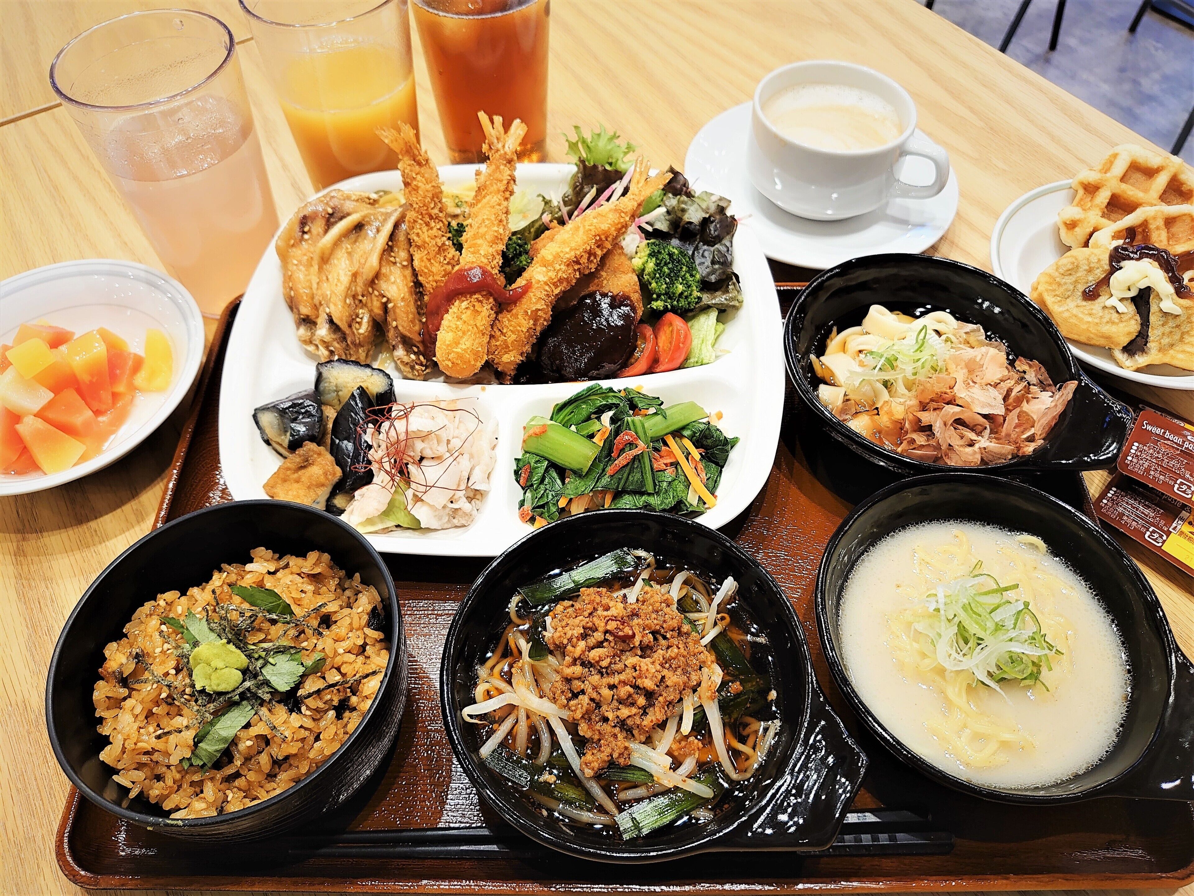 A tray with various dishes including fried items, salads, and bowls of rice and soup.