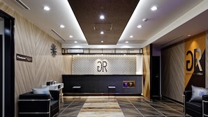 Un moderno vestíbulo de hotel con una recepción, zona de estar y señalización que indica el restaurante.