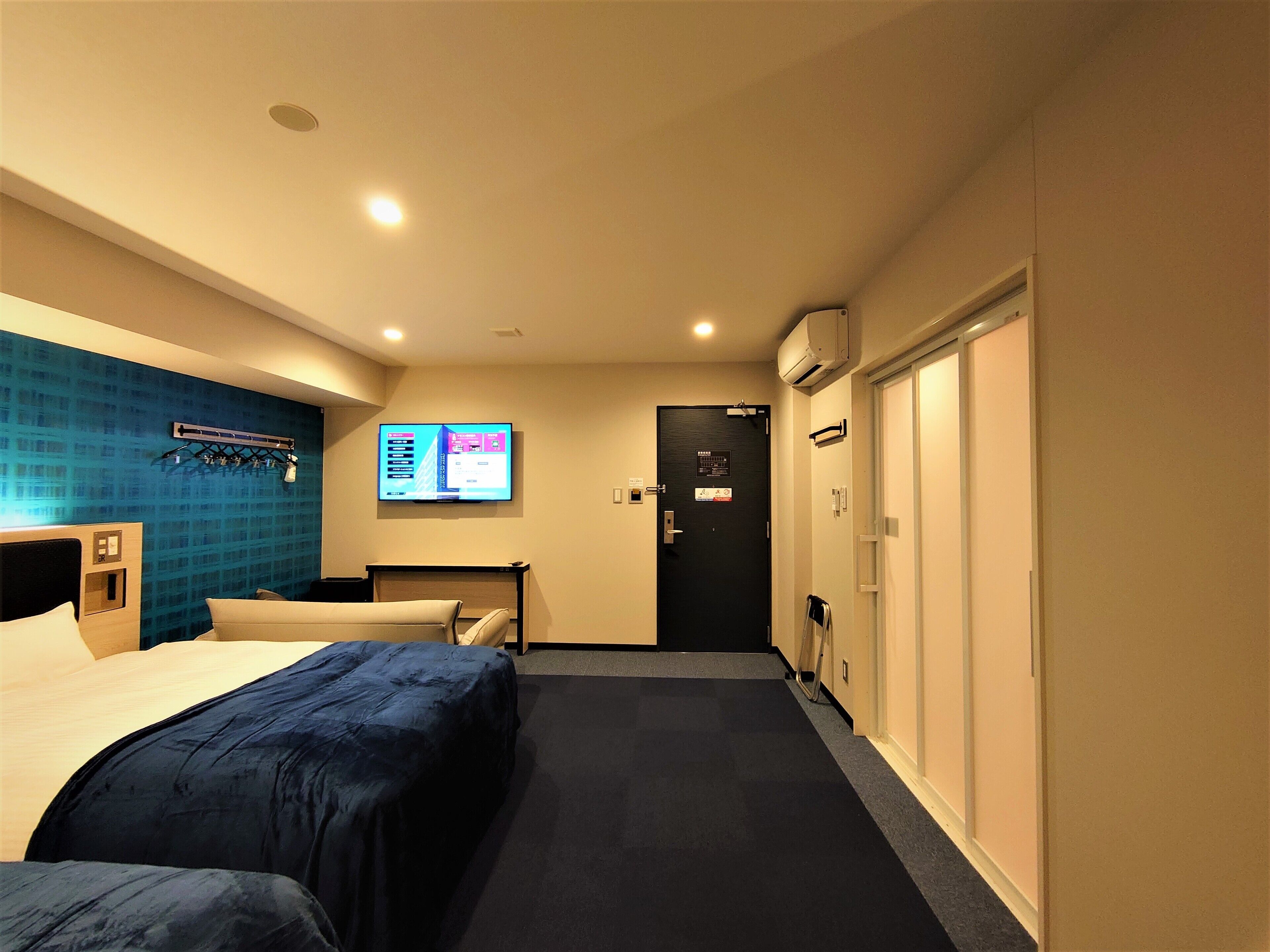 A hotel room with a bed, a desk, a TV, and a wardrobe.
