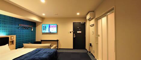 A hotel room with a bed, a desk, a TV, and a wardrobe.