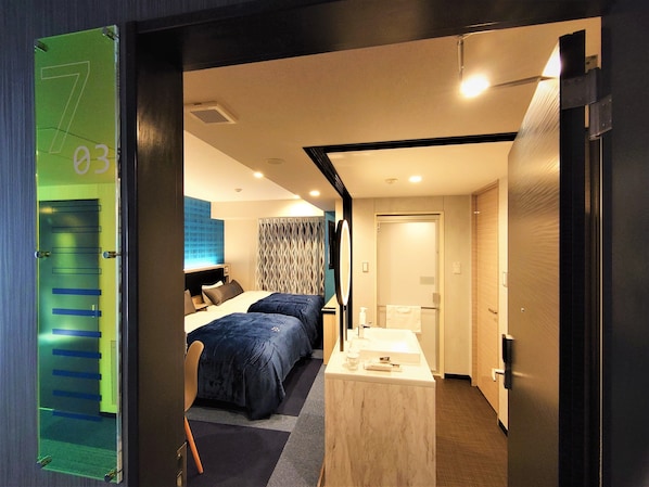 A hotel room with a bed, bedside table, and a bathroom with a sink and mirror. - Green Rich Hotel Nagoya Nishiki Artificial Hot Spring Futamata Yunohana (Nagoya)