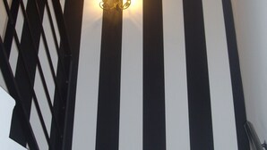 A staircase with black and white striped walls, a wooden handrail, and a wall-mounted light fixture. - Rural House TR-CC-00153 Cerezo Norte Cáceres Region Tierras Granadilla-Cáparra (Cerezo)