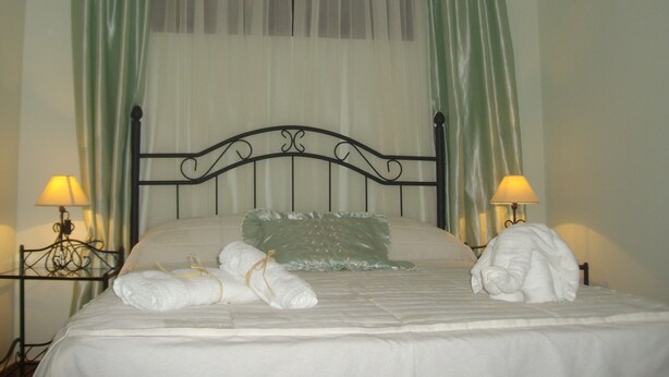 A neatly made bed with white linens and pillows, two bedside lamps, and sheer green curtains. - Rural House TR-CC-00153 Cerezo Norte Cáceres Region Tierras Granadilla-Cáparra (Cerezo)