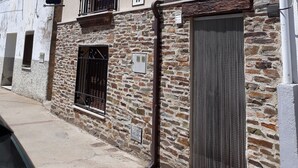A two-story building with a stone facade, a balcony with wrought iron railings, and a large metal gate. - Rural House TR-CC-00153 Cerezo Norte Cáceres Region Tierras Granadilla-Cáparra (Cerezo)