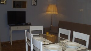 A dining area with a table set for two, a television, and a lamp. - Rural House TR-CC-00153 Cerezo Norte Cáceres Region Tierras Granadilla-Cáparra (Cerezo)