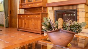 A wooden cabinet with glass doors, a fireplace, and a table with a terracotta pot containing plants. - Almenas del Cid rural house (Almonacid de Toledo)