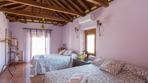 A room with two beds, a wooden ceiling, an air conditioner, and a window with curtains. - Almenas del Cid rural house (Almonacid de Toledo)