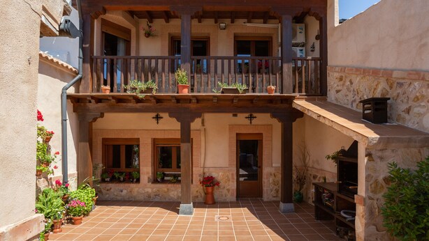 A courtyard with a wooden balcony, potted plants, and stone walls. - Almenas del Cid rural house (Almonacid de Toledo)