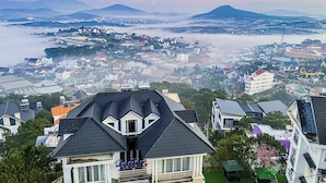 Zona residencial con casas, un edificio destacado con un letrero y montañas al fondo.