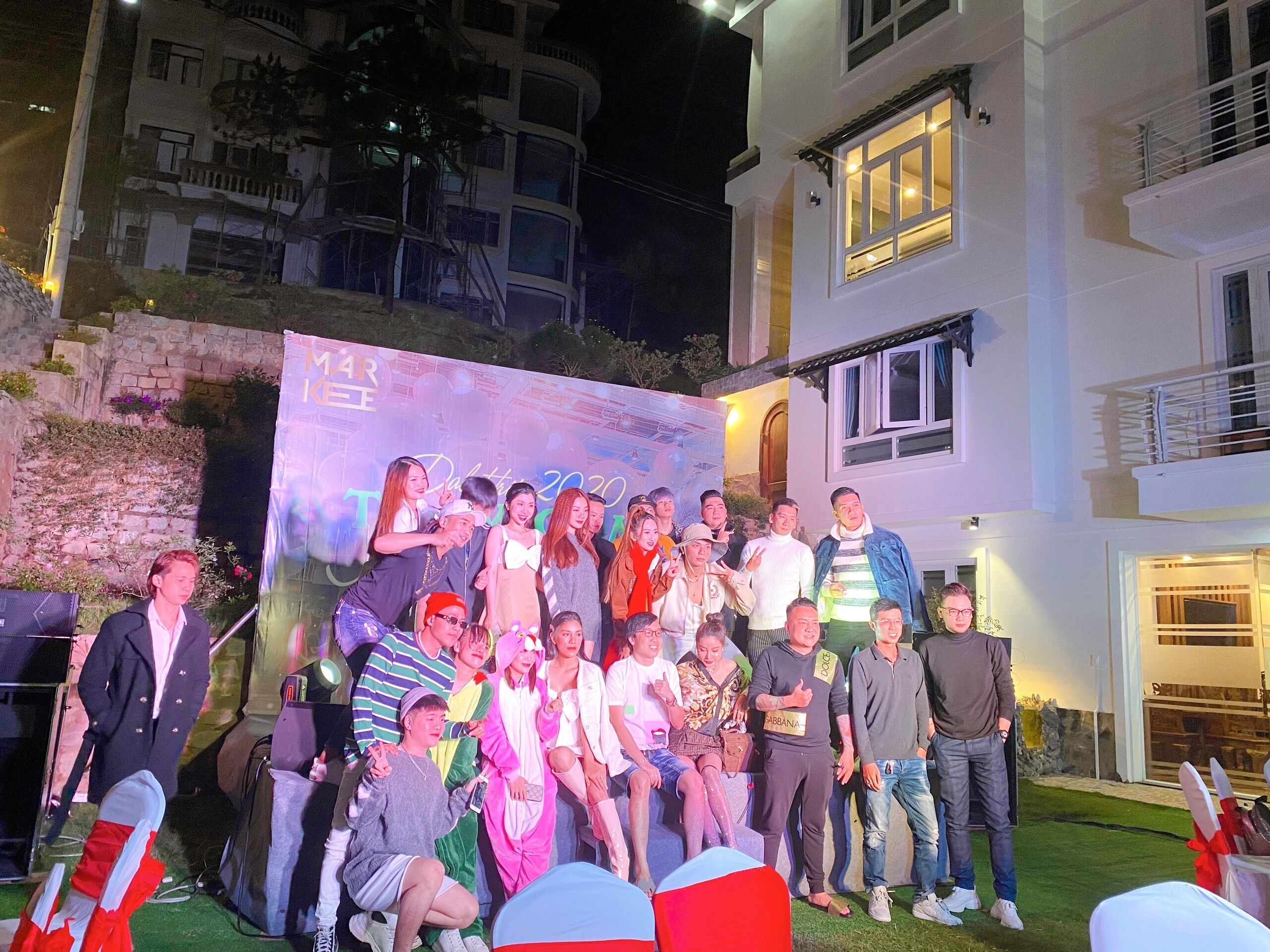 A group of people posing in front of a building with a banner.