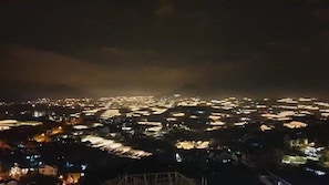 Une vue nocturne d’une zone densément peuplée, avec de nombreux immeubles et rues illuminés par un éclairage artificiel.