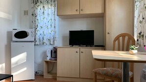 A compact kitchen with a microwave, stove, and a television on a cabinet. - Chaletparc Krabbenkreek (Sint-Annaland)