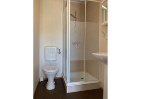 Un baño con inodoro, cabina de ducha y lavamanos.