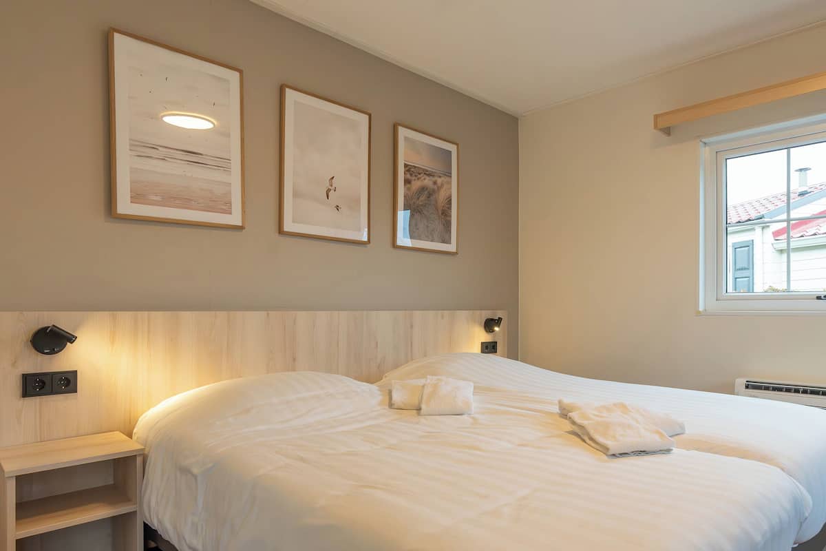 A bedroom with a large bed, a bedside table, and wall-mounted artwork.
