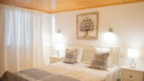 Ein Schlafzimmer mit einem Bett, zwei Nachttischen, einer Lampe, einem Fenster mit Vorhängen und einem gerahmten Bild an der Wand.