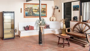 Ein Zimmer mit einem weißen Sofa, einem Holztisch, einer Glasvitrine und einem Gemälde an der Wand.