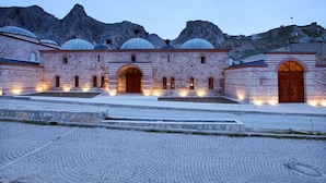 A historic building with multiple domes and arched entrances, set against a mountainous backdrop. - Royal Otel (Tokat)