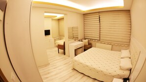 A bedroom with a bed, bedside table, chair, and a mirror. - Royal Otel (Tokat)