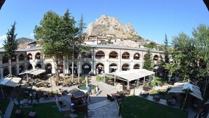 A courtyard with outdoor seating, a central fountain, and a building with multiple arches and balconies. - Royal Otel (Tokat)