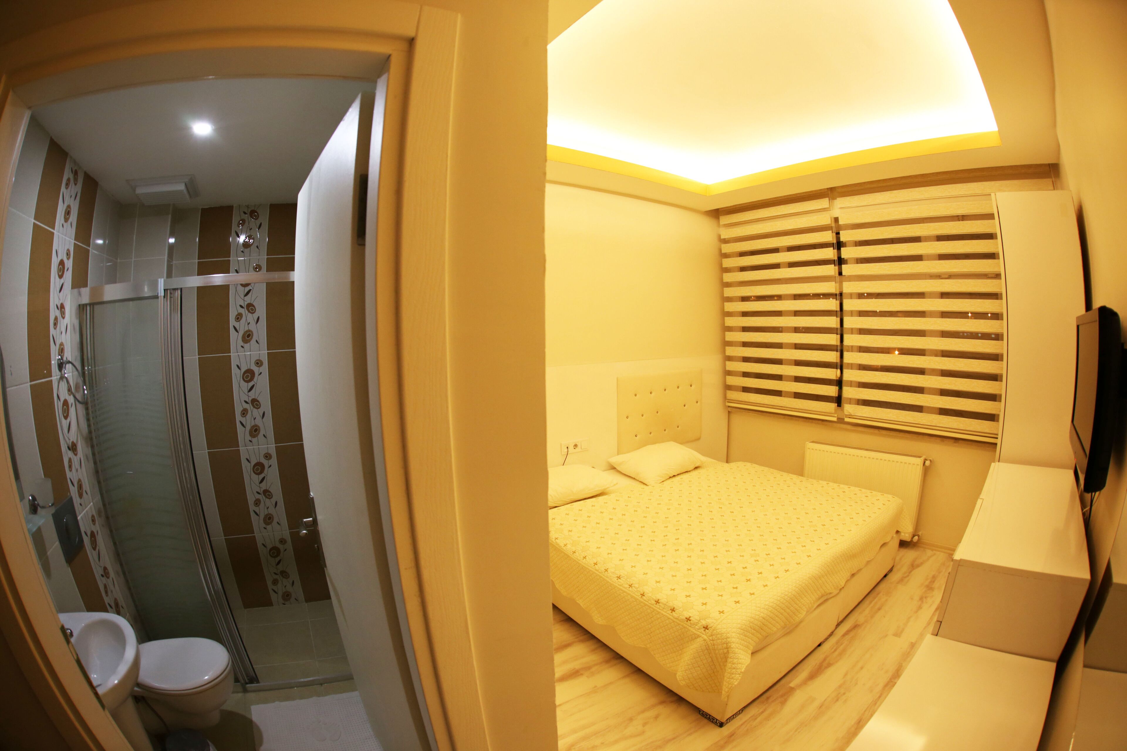 Une salle de bain avec douche, toilettes et lavabo. La pièce est dotée d’un sol carrelé et de murs ornés d’un motif floral.