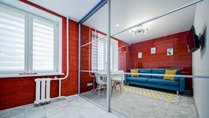 Una sala de estar moderna con un sofá azul, un separador de vidrio y una pared de ladrillo rojo.