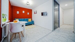 Una sala de estar moderna con un sofá azul, una mesa blanca y una pared de ladrillo rojo.