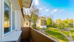 Un balcón con vistas a un parque verde, un parque infantil y edificios residenciales.