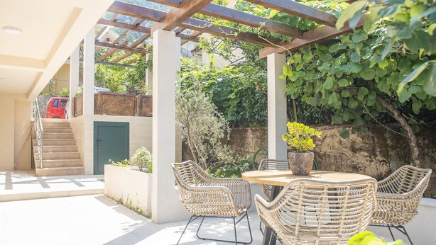 Un patio couvert aménagé avec des meubles en osier, une table et une plante en pot.
