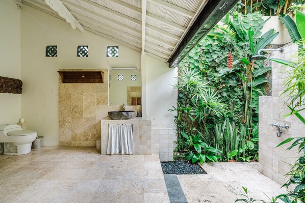 A bathroom with a large sink, a toilet, and a shower area.