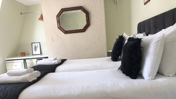 A neatly made double bed with white linens, a dark headboard, and a large mirror on the wall. - NO LONGER AVAILABLE FOR RENTAL (Kemptown)