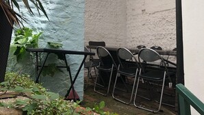 A small outdoor seating area with a white wall and a metal railing. - NO LONGER AVAILABLE FOR RENTAL (Kemptown)